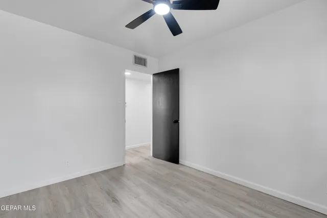 an empty room with wooden floor and ceiling fan
