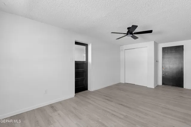a view of empty room with wooden floor and ceiling fan