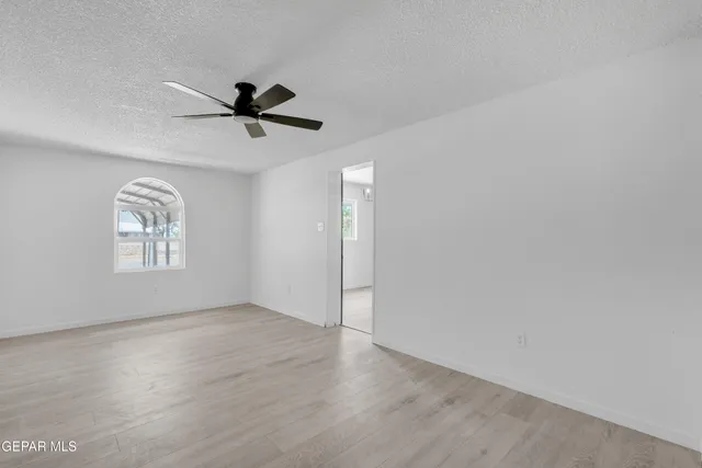 an empty room with a window and a ceiling fan