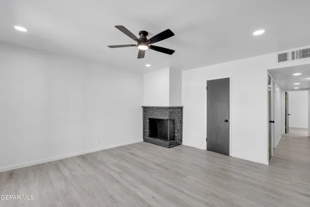 a view of empty room with wooden floor and fireplace