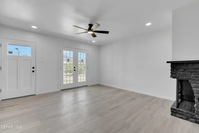 a view of an empty room with a window and wooden floor