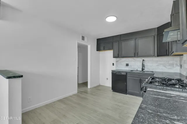 a kitchen with stainless steel appliances granite countertop a stove top oven a sink and a refrigerator