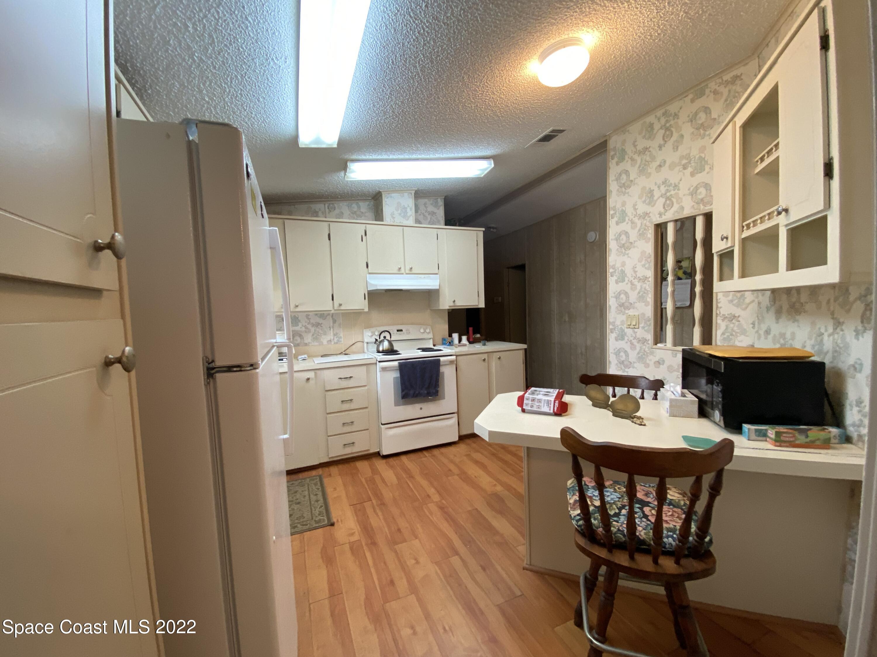 1352 Barefoot Circle Barefoot Bay, FL 32976 - Photo 17 of 40 a open dining room with stainless steel appliances kitchen island granite countertop a refrigerator a stove a sink with a dining table and chairs