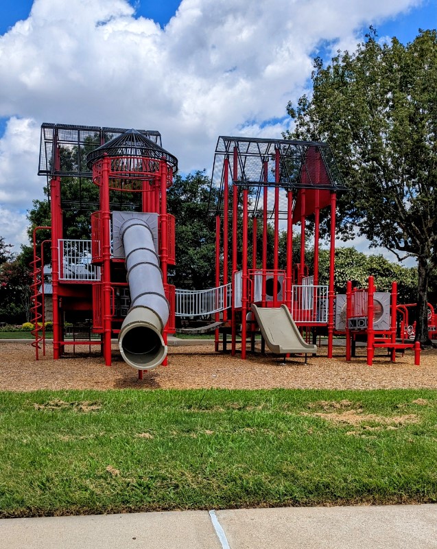20909 Springport Court Katy, TX 77450 - Photo 37 of 39 Charming playground featuring vibrant red structures, slides, and a tube slide, set amidst lush greenery—ideal for family-friendly living.