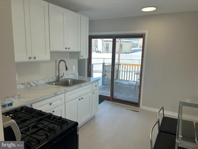 a kitchen with granite countertop a stove a sink and white cabinets