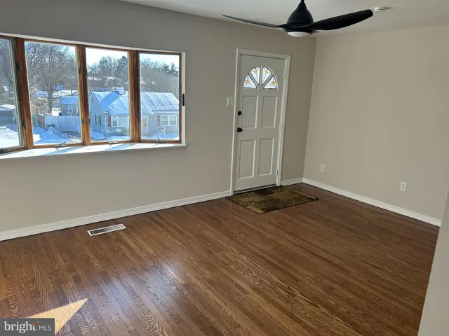 a view of empty room with wooden floor and fan