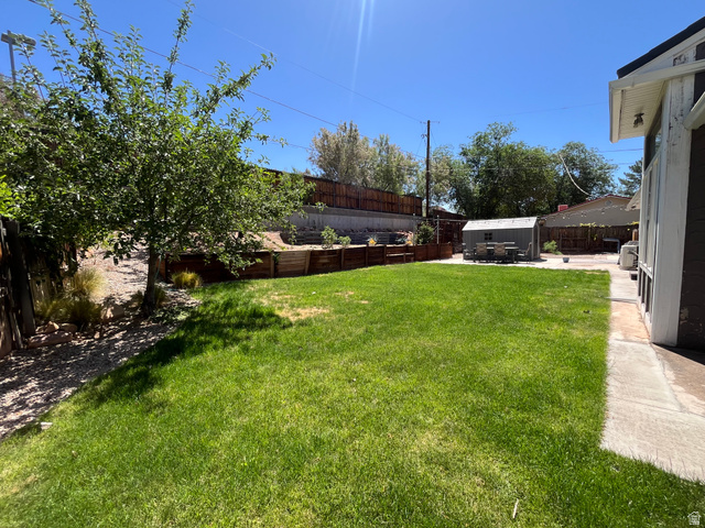 278 Hobbs Street Moab, UT 84532 - Photo 43 of 43 Spacious backyard featuring a manicured lawn, a concrete patio, and a storage shed