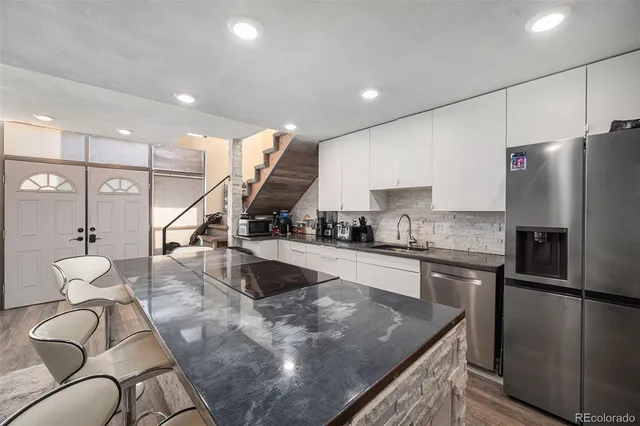 a kitchen with stainless steel appliances granite countertop a sink a stove and a refrigerator