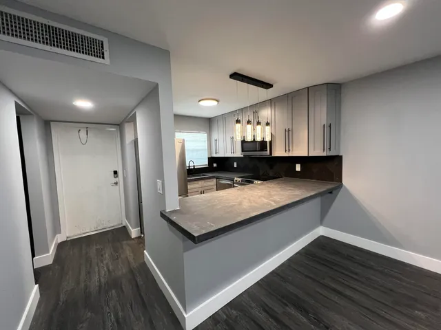 a kitchen with stainless steel appliances granite countertop a refrigerator a sink dishwasher a stove and white countertops with wooden floor