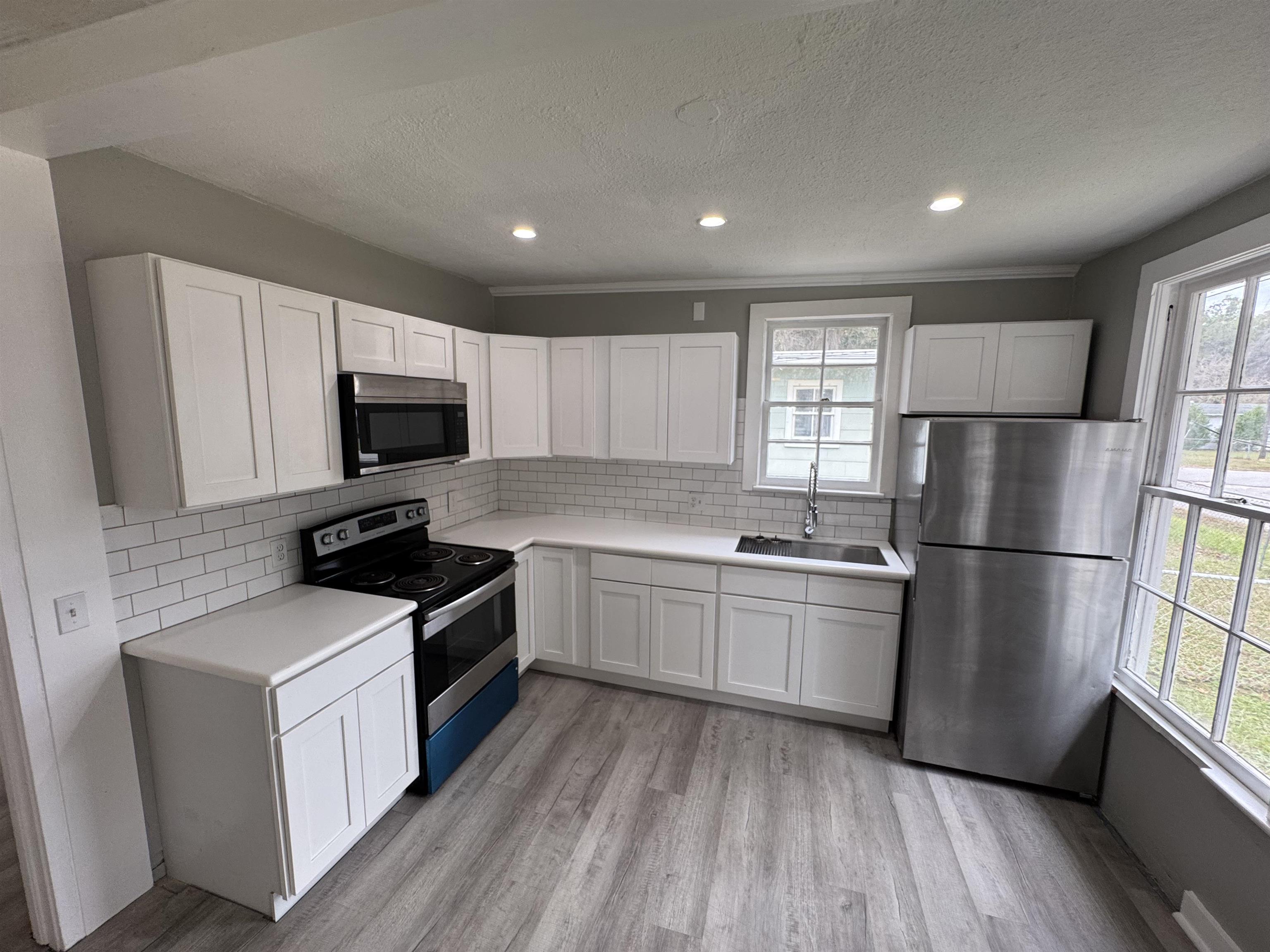 2909 Lane Street Palatka, FL 32177 - Photo 6 of 21 a kitchen with a sink a refrigerator a microwave and cabinets