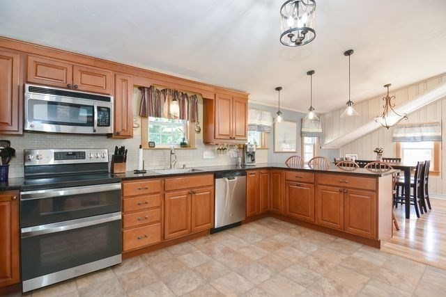 127 Haverhill Road Amesbury, MA 01913 - Photo 7 of 42 a kitchen with stainless steel appliances granite countertop a stove top oven a sink dishwasher a dining table and chairs with wooden floor