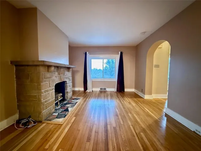 a view of empty room with wooden floor and fireplace
