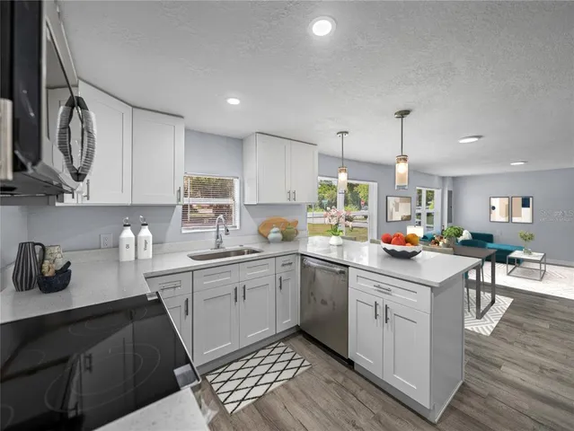 a kitchen with a sink dishwasher a stove a microwave oven and cabinets with wooden floor