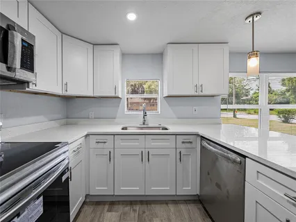 a kitchen with cabinets appliances a sink and a window