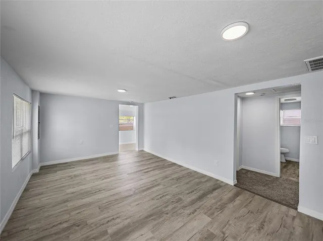 a view of an empty room with wooden floor and a window