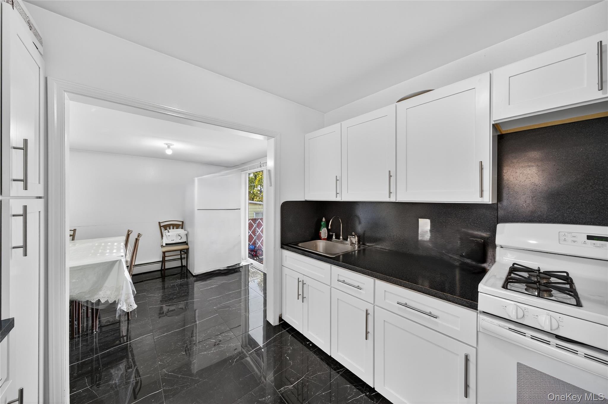 469 Hillside Road Monroe, NY 10950 - Photo 8 of 44 Kitchen with white gas range, white cabinetry, decorative backsplash, and baseboard heating