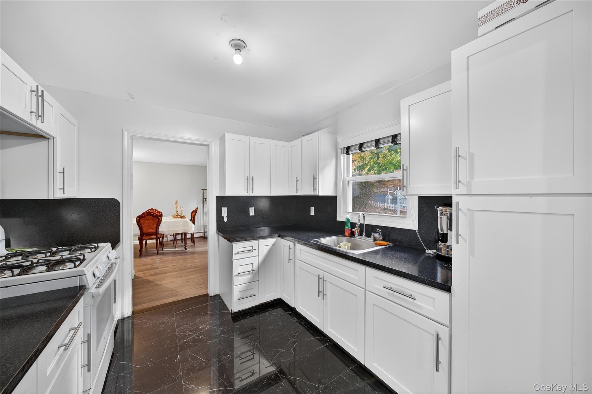 469 Hillside Road Monroe, NY 10950 - Photo 9 of 44 Kitchen featuring white gas range oven, white cabinetry, dark marble finish flooring, tasteful backsplash, and dark stone counters