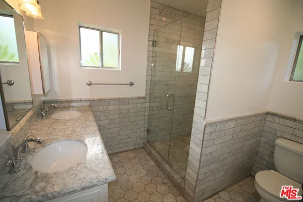 a bathroom with a granite countertop shower a toilet and a sink