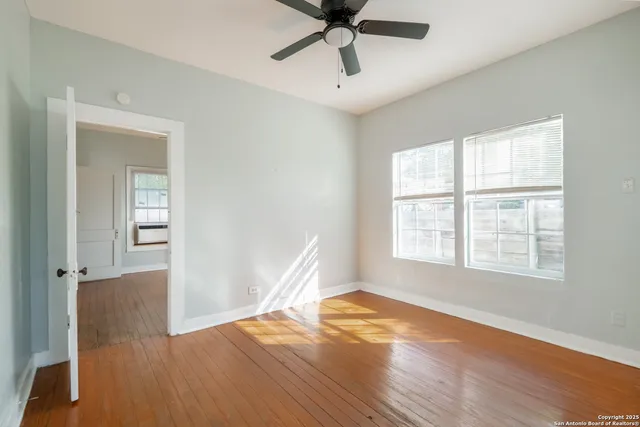 a view of an empty room with wooden floor and a window