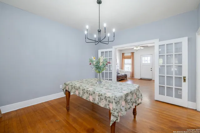 a dining room with wooden floor a chandelier a wooden table and chairs