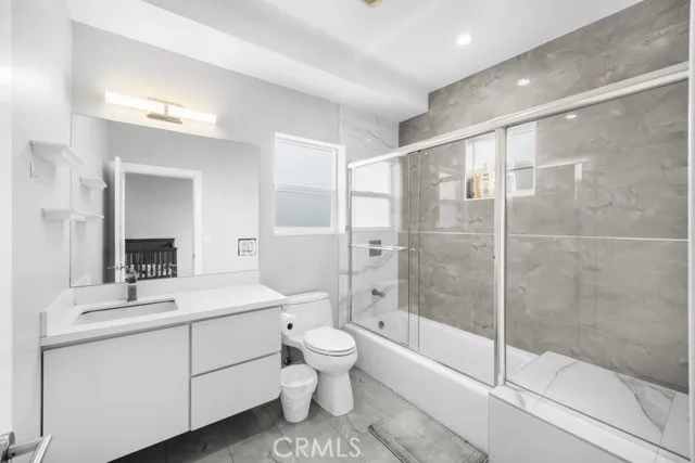 a bathroom with a shower sink vanity mirror and toilet