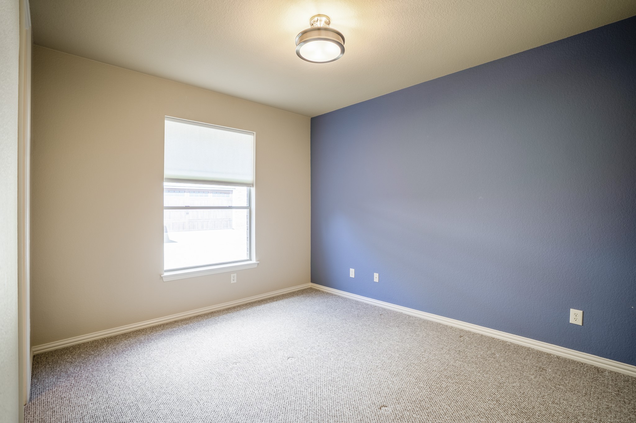 2407 Hendricks Lakes Drive Spring, TX 77388 - Photo 26 of 50 Returning to the front of the home, this secondary bedroom suite sits near the office/study and offers a quieter transition from the main living areas. The window brings in natural light, while the blue accent wall adds contrast and gives the room a defined, finished feel before the walkthrough continues into the nearby bath.