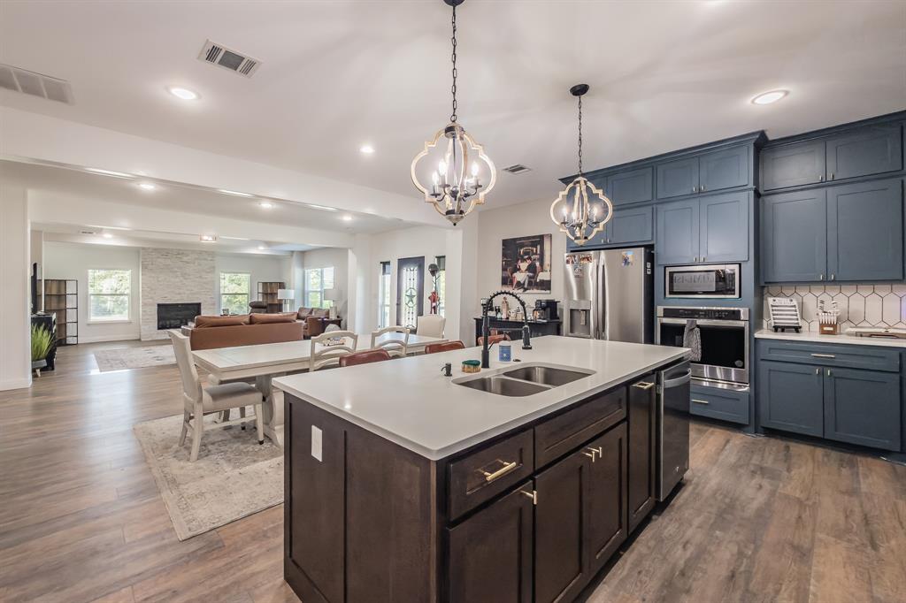 117 Rock Salt Drive Springtown, TX 76082 - Photo 8 of 38 Gourmet kitchen featuring a large central island with an undermount double sink, white quartz countertop, and dark wood cabinetry with gold hardware