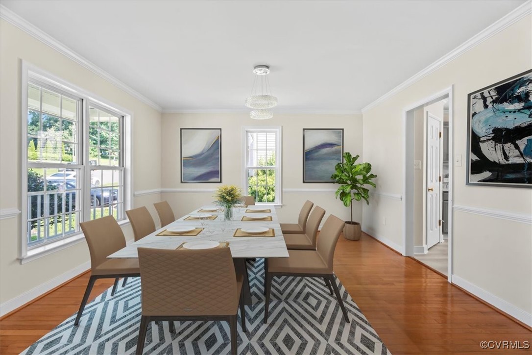 Dining space with wood finished floors and crown m