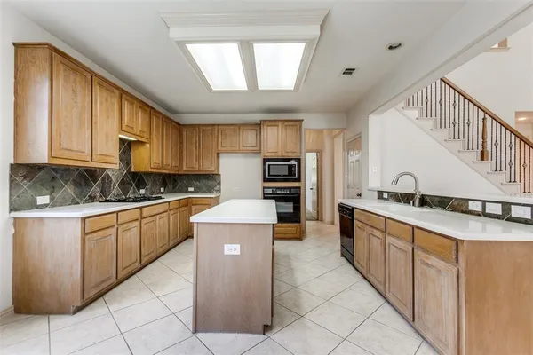 a kitchen with stainless steel appliances granite countertop a stove top oven a sink a counter top space and cabinets