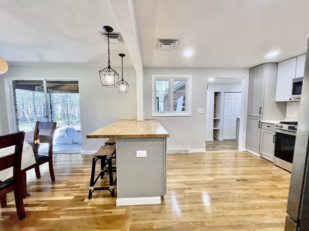 17 Brentwood Road Sudbury, MA 01776 - Photo 15 of 34 a living room kitchen with stainless steel appliances kitchen island granite countertop a table chairs and a refrigerator