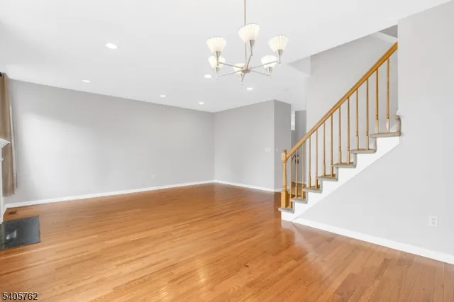 a view of an empty room with wooden floor and staircase