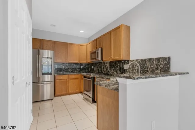 a kitchen with stainless steel appliances granite countertop a refrigerator and a stove top oven