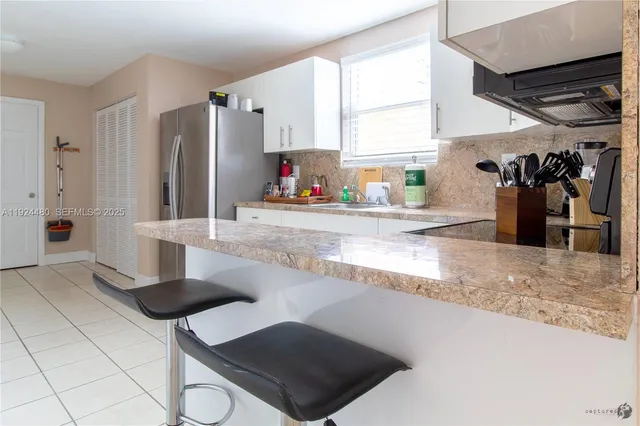 a kitchen with stainless steel appliances kitchen island granite countertop a refrigerator and a sink