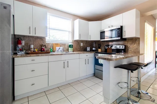 a kitchen with stainless steel appliances kitchen island granite countertop white cabinets sink and white appliances