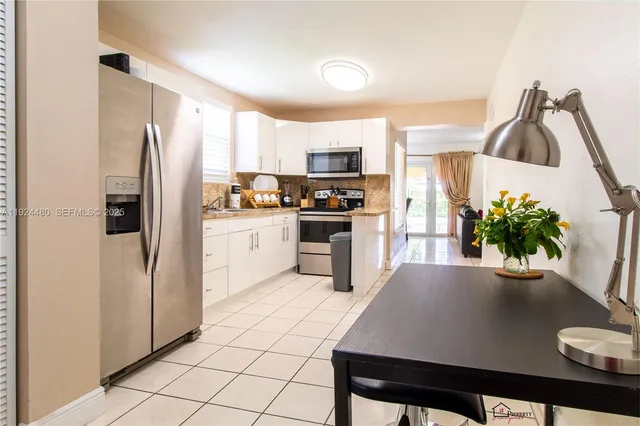 a kitchen with stainless steel appliances granite countertop a refrigerator a sink a stove a dining table and chairs
