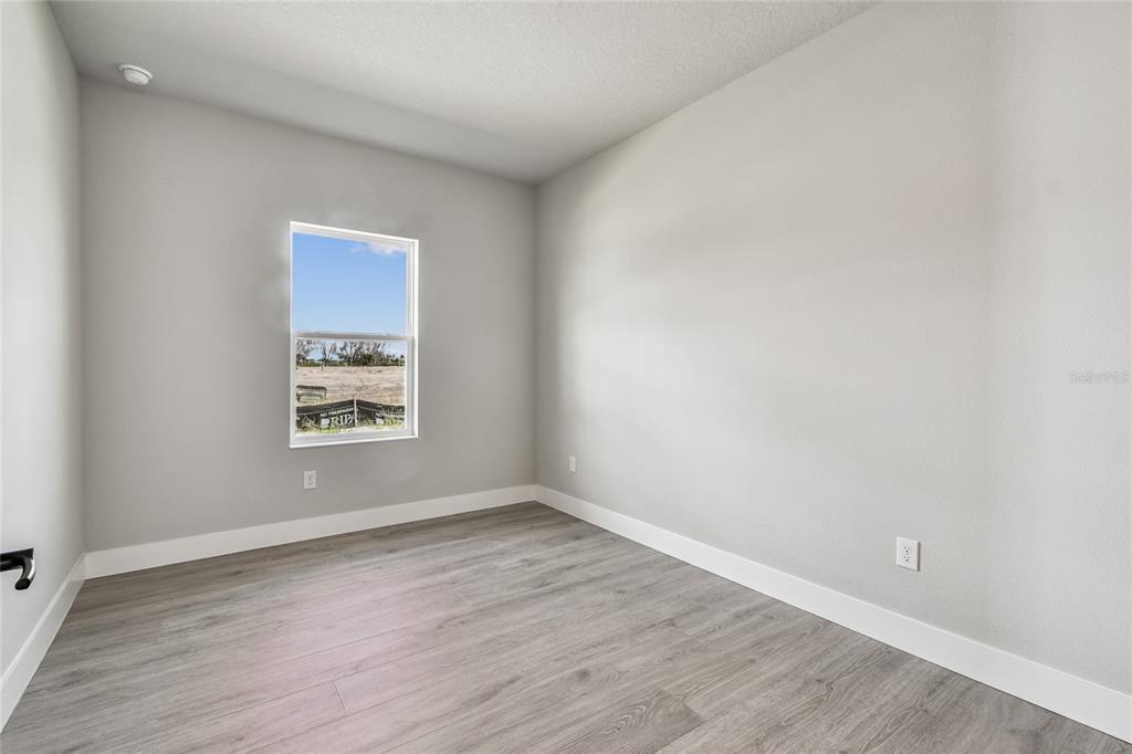 11743 Full Moon Loop Parrish, FL 34219 - Photo 15 of 42 a view of an empty room with wooden floor and a window