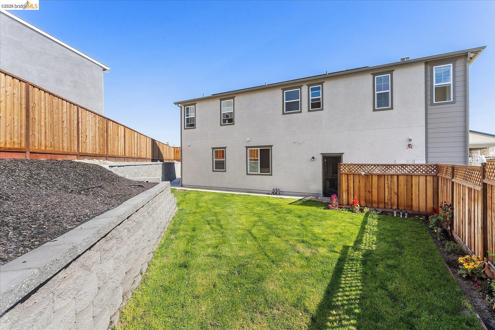 5601 Ridgepoint Way Antioch, CA 94531 - Photo 48 of 59 Rear exterior of the property featuring a manicured lawn, block retaining wall, and wood fencing