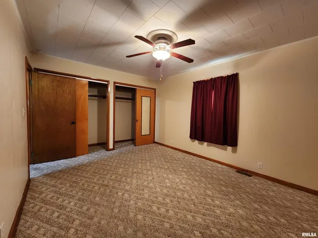 a view of an empty room with window and chandelier fan