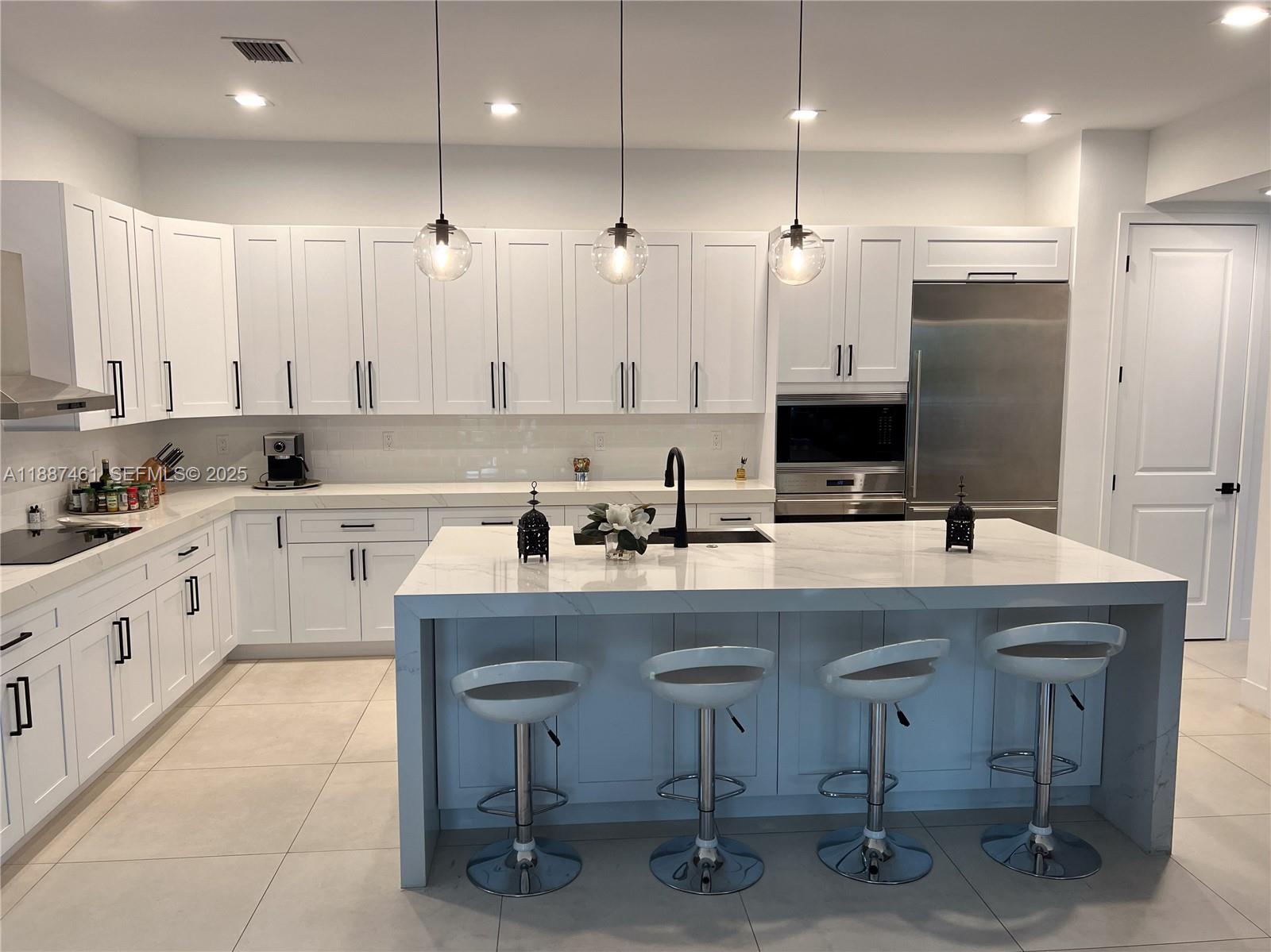 8904 Southwest 69th Trail Miami, FL 33173 - Photo 16 of 42 a kitchen with furniture a sink a center island and stainless steel appliances