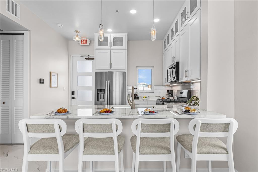 855 Lagoon Street, Unit 4 Fort Myers Beach, FL 33931 - Photo 27 of 40 a kitchen with white cabinets and chairs