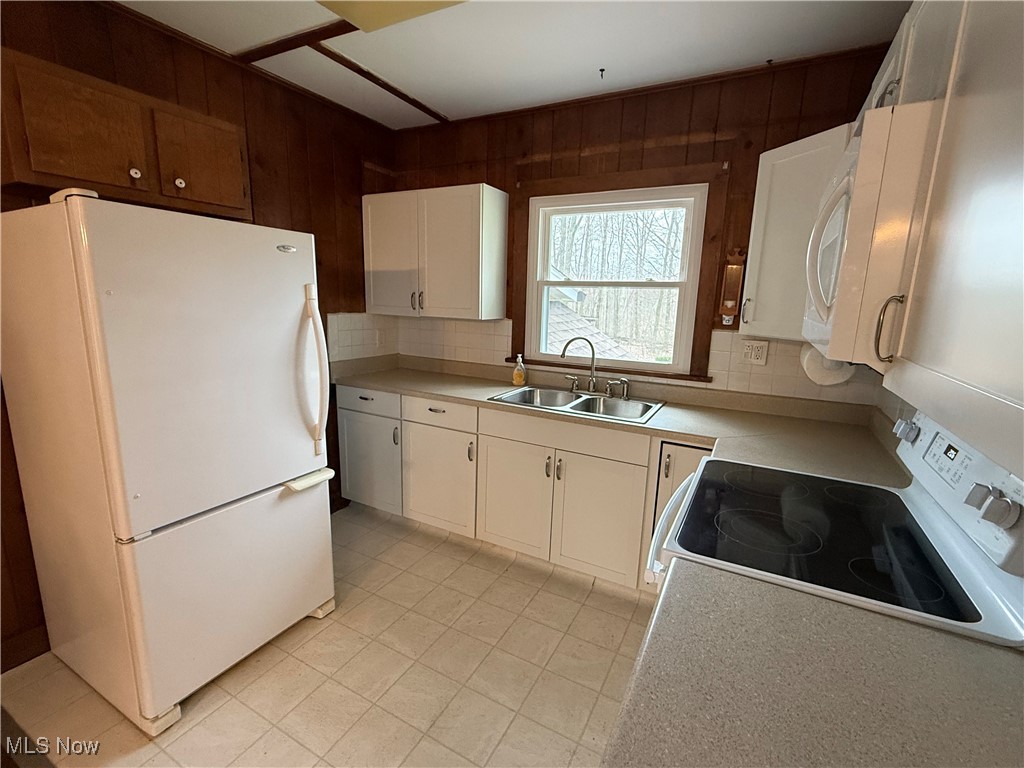 3122 South Medina Line Road Wadsworth, OH 44281 - Photo 24 of 41 Kitchen with white appliances, white cabinetry, a sink, and wooden walls