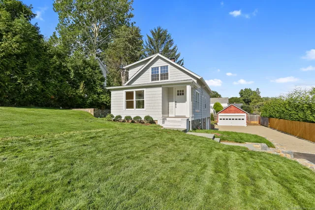 a front view of a house with a yard and trees