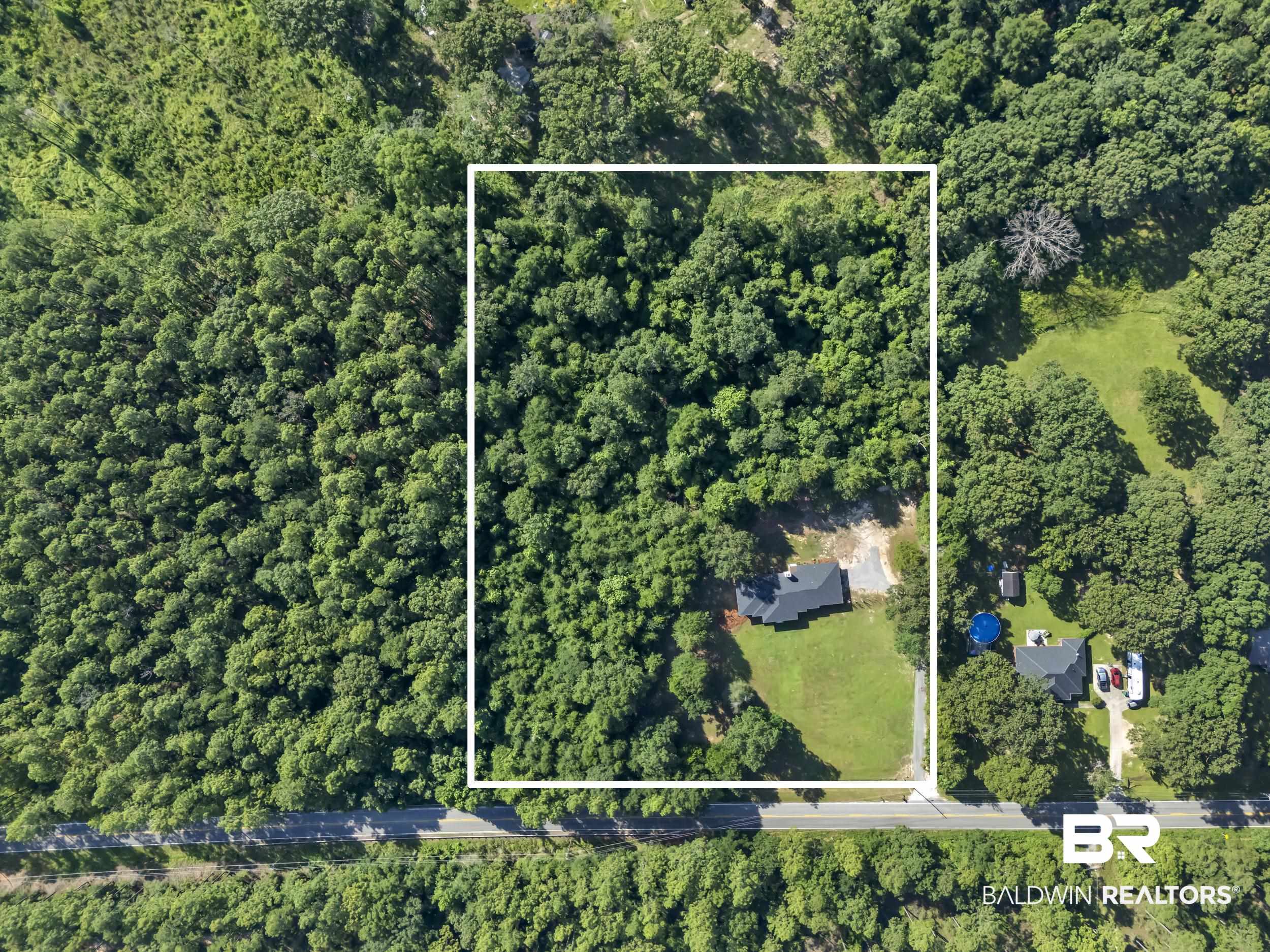 8170 Wilmer Georgetown Road Wilmer, AL 36587 - Photo 27 of 31 Expansive wooded lot featuring a single-story residence with a dark roof and a cleared yard space