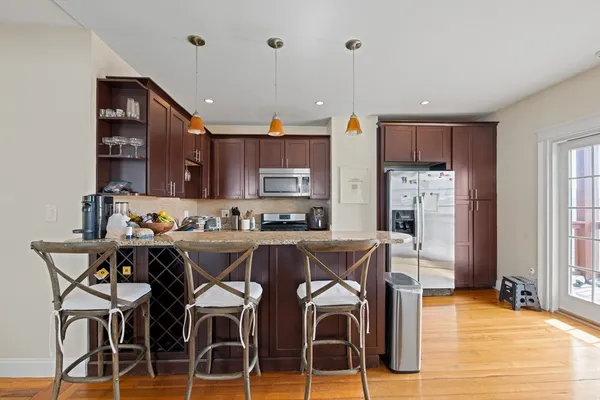 a kitchen with stainless steel appliances a dining table chairs and wooden floor