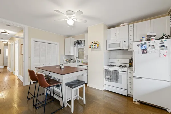 a kitchen with stainless steel appliances a stove a sink dishwasher a refrigerator with white cabinets and wooden floor
