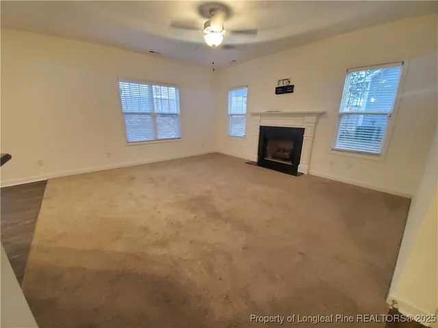 an empty room with windows and fireplace