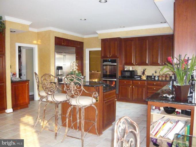 4801 Broom Drive Olney, MD 20832 - Photo 3 of 19 a kitchen with stainless steel appliances kitchen island granite countertop a table and chairs in it