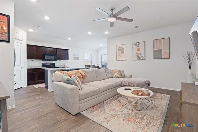 a living room with furniture flat screen tv and kitchen view