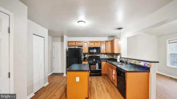 a kitchen with stainless steel appliances granite countertop a stove top oven a sink dishwasher a dining table and chairs with wooden floor