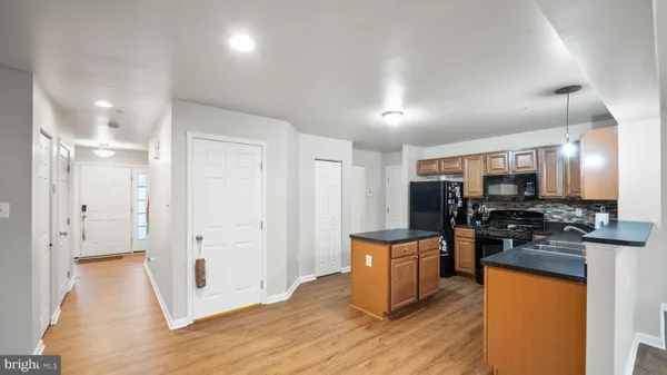 a kitchen with stainless steel appliances granite countertop a stove top oven a sink dishwasher and a refrigerator with wooden floor